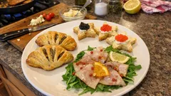 Tři rybí předkrmy na jednom tácu: vějířky z listového těsta, tartinky a carpaccio